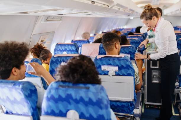 hôtesses de l’air servant de la nourriture et des boissons au client dans l’avion pendant le vol - chariot à roulettes photos et images de collection