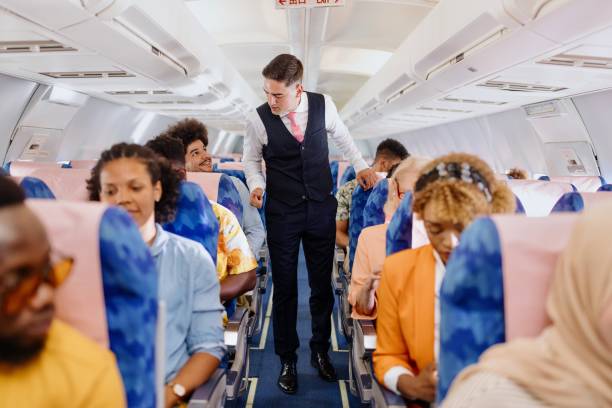 istock Male Cabin Crew member walks down the aisle checking on passengers 1401029753
