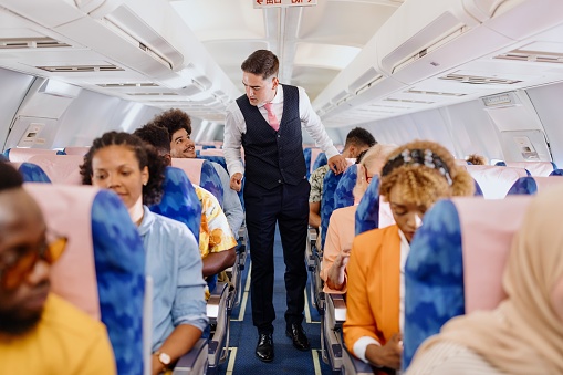 Male flight attendant checking on the passengers before take off