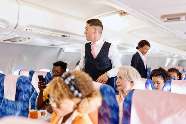 istock Male flight attendant checking on the passengers before take off 1401029774