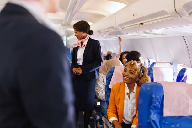 istock Female Cabin Crew member walks down the aisle checking on passengers 1401029801