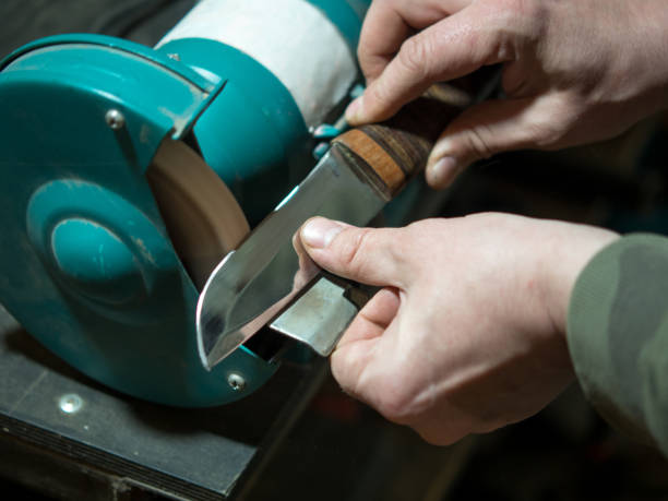 istock Knife sharpener and a hand with a blade, a man sharpens a knife on a grinder 1401030166