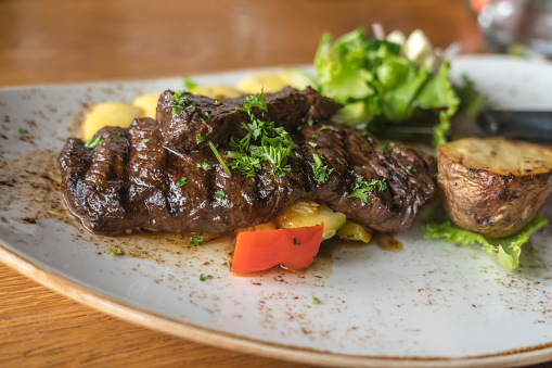 Sliced medium rare grilled Beef steak Striploin and salad with tomatoes and arugula on white plate isolated