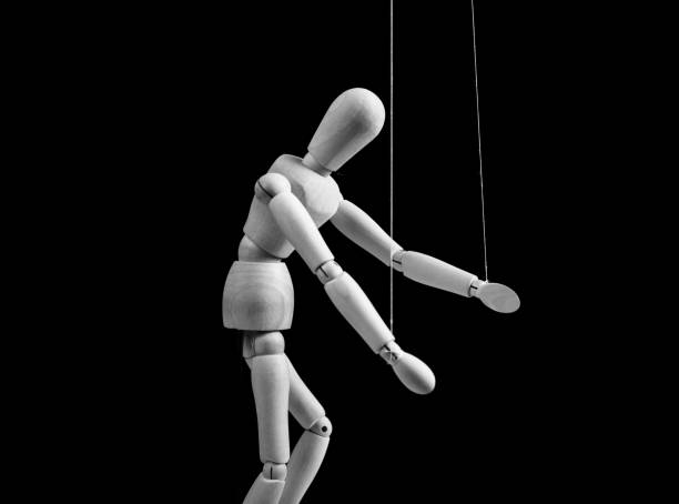 istock Puppet on strings. Slavery, violence, negative influence, addiction concept. Marionette in human hand. Black and white. 1401030953