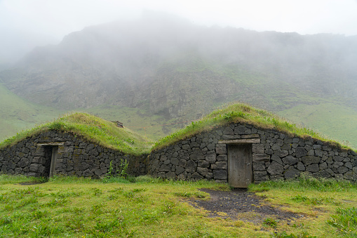 Icelandic turf houses on Heimaey island, made of black rocks on rainy day. Iceland