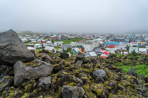 Black volcanic rocky and colorful houses of Vestmannaeyar town, view from the hill. Heimaey island,  on Westman Islands.
