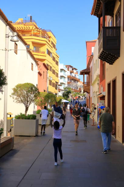 Hustle and bustle in a Busy street with Colourful houses November 20 2021 - Puerto de la Cruz, Tenerife, Canary Islands, Spain: Colourful houses and tourists in the centre of village puerto de la cruz tenerife stock pictures, royalty-free photos & images