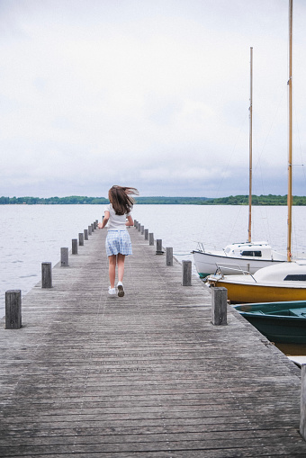 A girl running at the end of a jetty on a lake