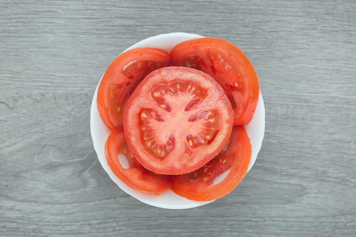 Sliced tomato in a bowl. Directly above view.