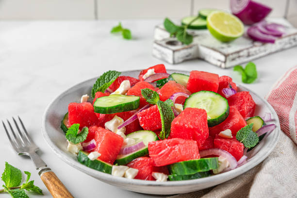 istock Summer salad with watermelon, cucumber, cheese and mint in a plate on white table with fork. close u 1401038078