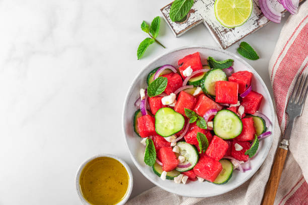 istock Summer salad with watermelon, cucumber, cheese and mint in a plate on white table. Top view with copy space 1401038098
