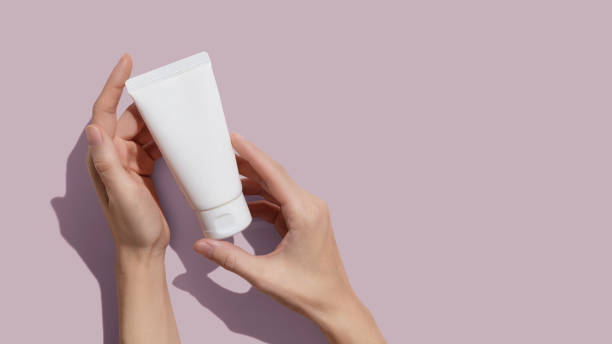 istock Young female hands holding blank white squeeze bottle plastic tube on pink background. Packaging of cream, lotion, gel, facial foam or skincare. Cosmetic beauty product branding mock-up. Copy space 1401043669