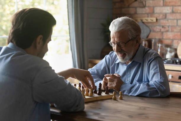 istock Smiling mature man with grownup son playing chess together 1401046634