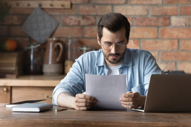 istock Confident man in glasses reading document, analyzing financial report 1401047425