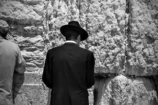 Jerusalem, Israel - May 20, 2009:  Orthodox Jew dressed in traditional jewish clothing prays by The Western Wall in Jerusalem. Black and white photography