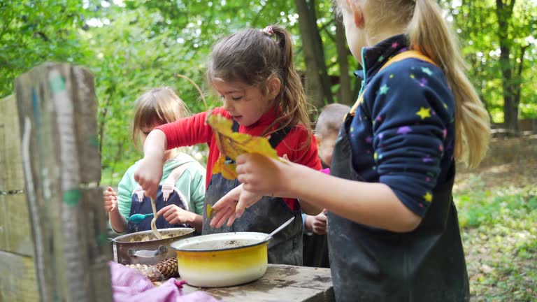 forest kindergarten Happy Preschool or school group children play Cook in swamp improvised kitchen. Outdoors small child have fun playing. Summer Camp