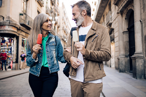 Portrait of a mature couple exploring Barcelona and enjoying ice cream on the move.