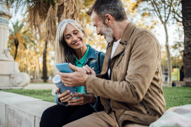 istock Happy mature couple on vacation walking and using smartphone 1401067082