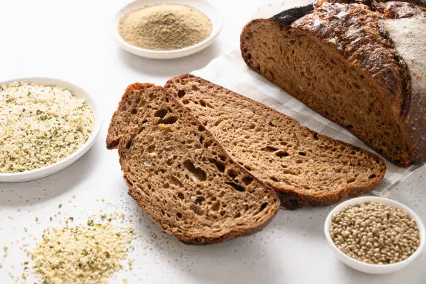 Loaf of Hemp bread, hempseeds and flour isolated on white background. Close up.