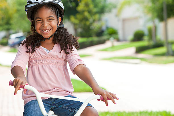 happy african american girl riding bike sonriendo - helmet bicycle little girls child fotografías e imágenes de stock
