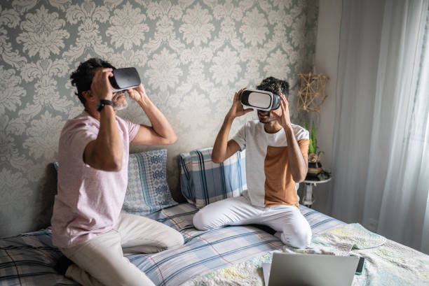 自宅でvrメガネで遊ぶゲイカップル - gamer watching tv adult couple ストックフォトと画像