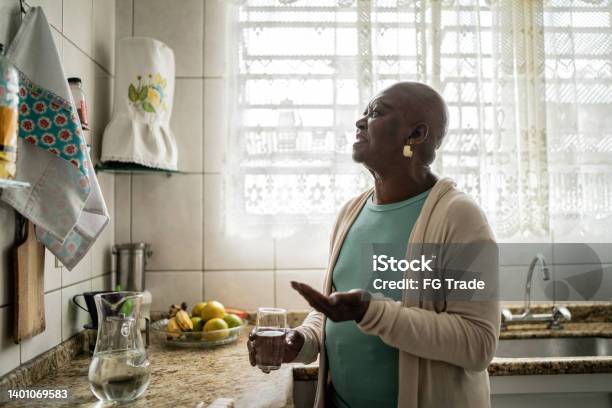 Contemplative Senior Woman Taking Medicine At Home Stock Photo - Download Image Now - Cancer - Illness, Patience, Taking Medicine
