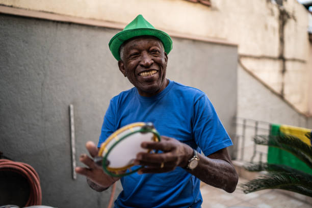 hombre mayor tocando la pandereta en casa - samba fotografías e imágenes de stock