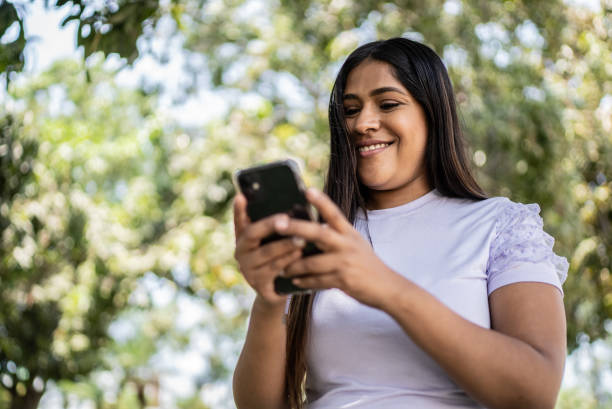 Woman using smartphone outdoors stock photo