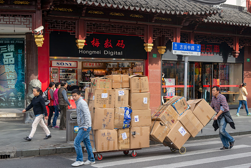 Shanghai, China - November 12, 2014: Men wheel large boxes on Fangbang Rd