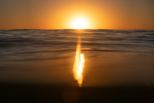 Shallow depth of field scene of sun setting over the ocean surface