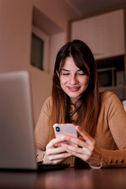 istock Female freelancer using smart phone while working late in home office 1401072753