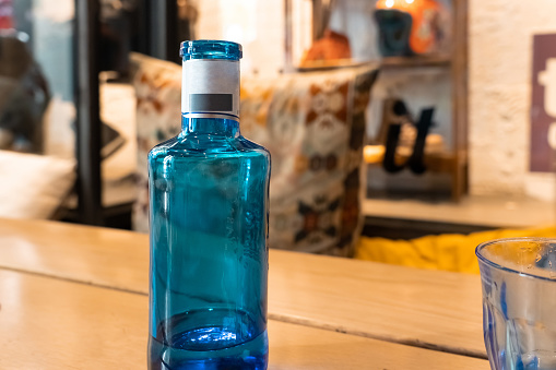 Blue glass bottle on a blurry colorful background. Water bottle