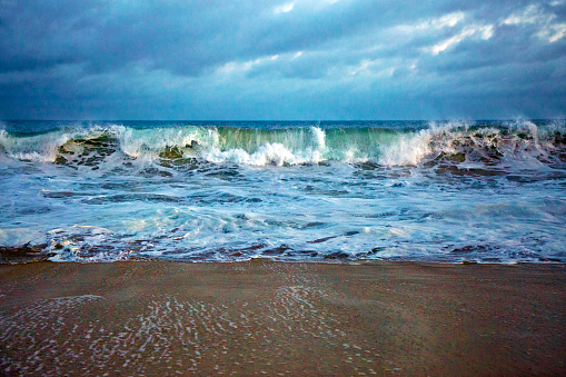 Cloudy evening, and beautiful colors as the waves are crashing on the beach.
