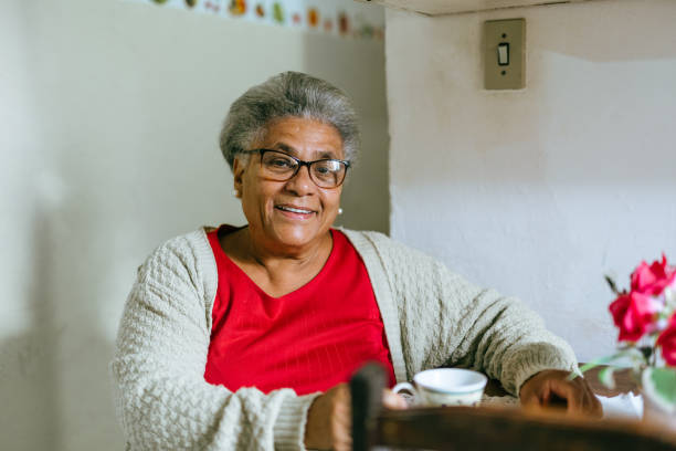 donna anziana sorridente che beve caffè a casa - 60s senior adult breakfast cheerful foto e immagini stock