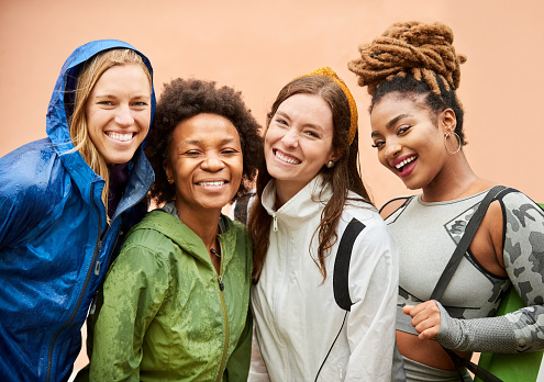 Group portrait of multiethnic sporty women standing together looking at camera and smiling on a rainy day