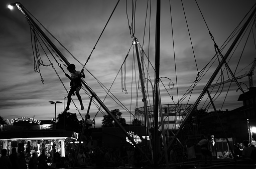 Parabiago, Italy - June 04, 2022: some boys are jumping, tied to harnesses as a multitude of people visit the amusement park in the city center