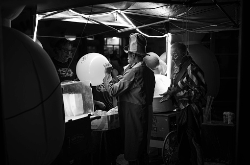 Parabiago, Italy - June 04, 2022: two men prepare balloons and sell them. scene portrayed during a summer party in the town center