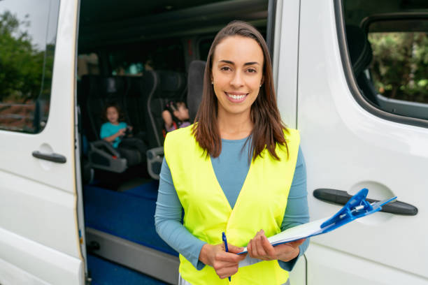 istock Teacher in charge of the school bus holding a tablet computer 1401090496