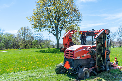 Jacobsen, a lawn mowing tractor is parked on the lawn in the park, Ontario, Canada.
