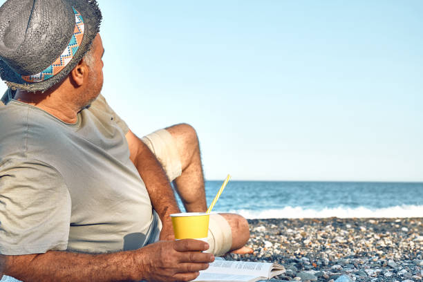 istock Back view of active middle aged man wearing straw hat relaxing at the beach and looking seaside. Concept of leisure activities, tourism, lifestyle e nature. Tourism in summertime. 1401098867