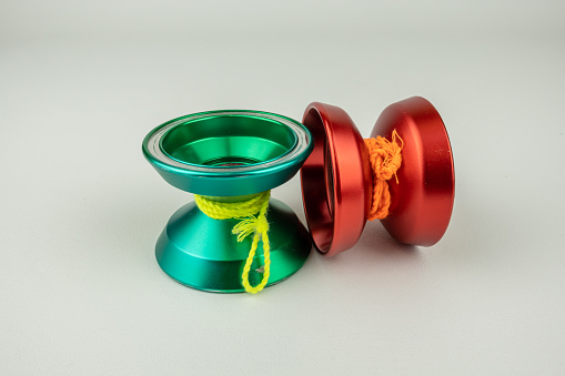 A pair of durable modern metal yoyo, green and red, isolated on a white background.