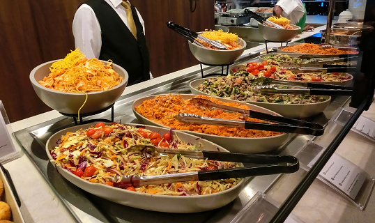 Woman taking food from Sorted fresh salads displayed on a buffet in restaurant