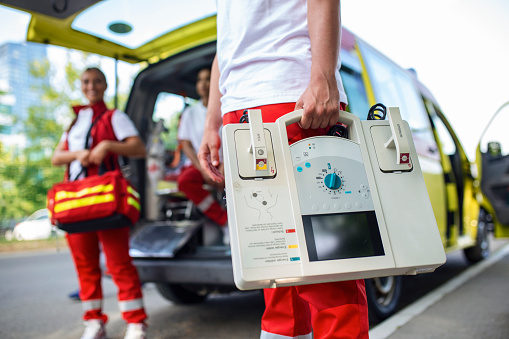 Hand of the doctor with defibrillator. Teams of the Emergency medical service are responding to an traffic accident.