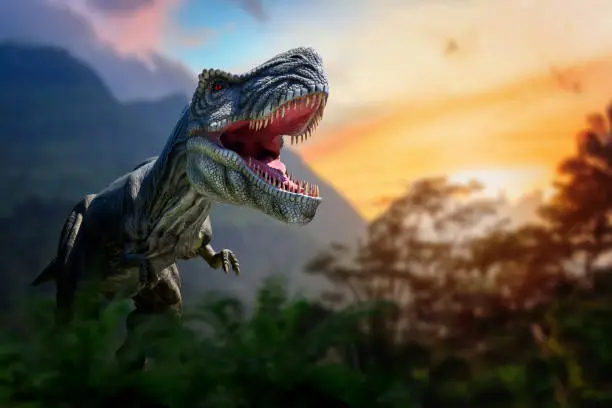 Photo of Tyrannosaurus Rex in the jungle. Huge dinosaur against the mountain background of a prehistoric forest at sunset