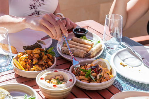 A Woman having dinner and reaching for food on a Table with different variety of traditional Lebanese food