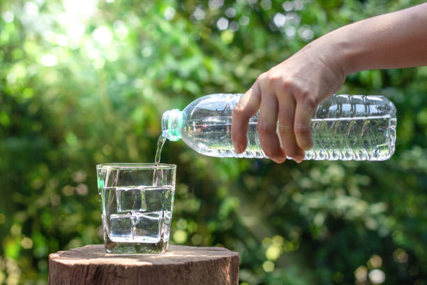 istock Hand holding drinking water bottle pouring water into glass 1401111783