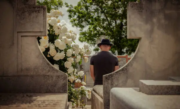 Rear view of adult man mourning in cemetery. Madrid, Spain