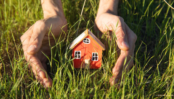 istock Hand hold house model on green grass background. Eco house concept 1401114050