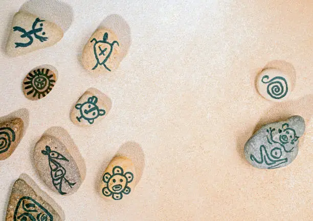 Stones with hand-drawn taino petroglyphs symbols, craft with children for Hispanic heritage month