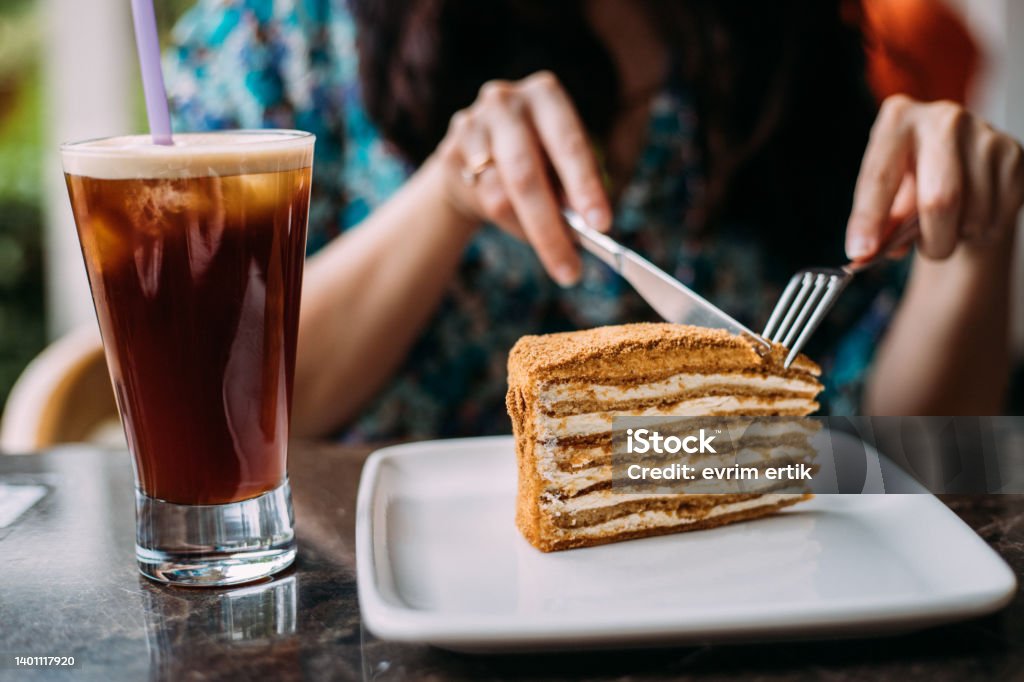 Eating honey cake and ice americano on a hot sunny day Adult Stock Photo